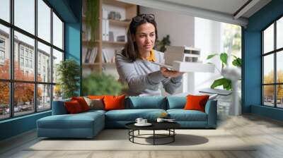 Architect with model of a house sitting at the desk indoors in office. Wall mural