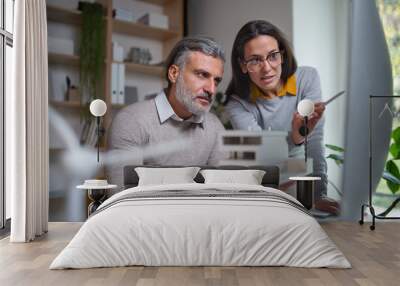 Architects with model of house sitting at the desk indoors in office, working. Wall mural