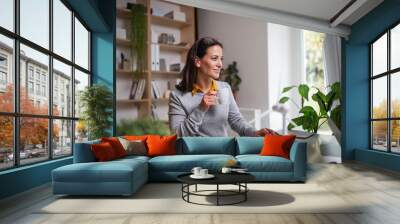 Attractive businesswoman sitting at the desk indoors in office, working. Wall mural