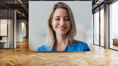 Banner of confident female doctor with closed eyes in hospital. Beautiful nurse wearing blue uniform, holding clipboard standing in modern private clinic. Wall mural