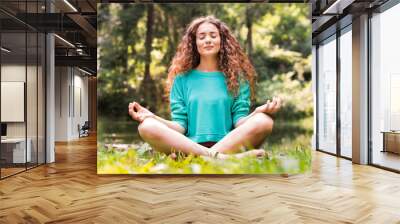 Beautiful girl practices yoga in the morning forest. Wall mural