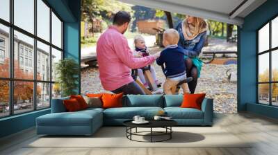 Beautiful young family with small twins playing on playground in autumn. Wall mural