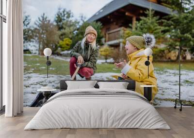 Boy with Down syndrome with his mother clearing snow from path with shovel in front of house. Wall mural