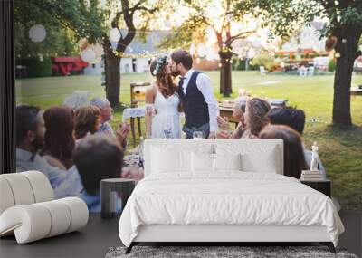 Bride and groom with guests at wedding reception outside in the backyard. Wall mural