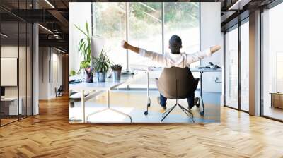 Businessman at the desk in his office stretching arms. Wall mural