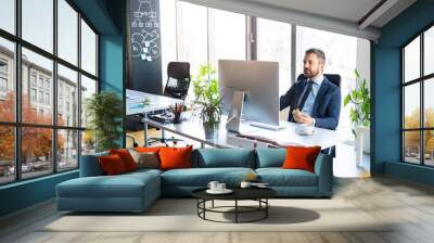 Businessman at the desk with computer in his office. Wall mural