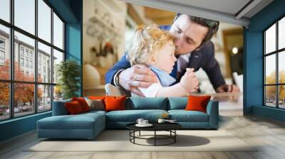 Businessman coming home, kissing little son on forehead. Wall mural