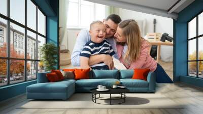 Cheerful down syndrome boy with parents indoors at home hugging, laughing. Wall mural