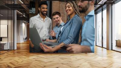 Cheerful young businesspeople with laptop working in office, social inclusion and cooperation concept. Wall mural