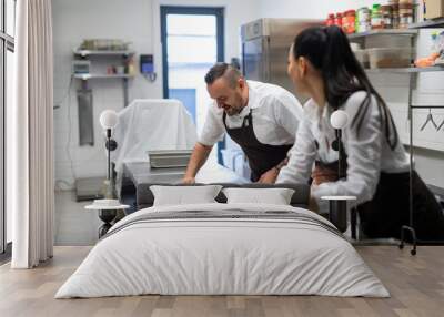 Chef and cook cleaning the workspace after doing dishes indoors in restaurant kitchen. Wall mural