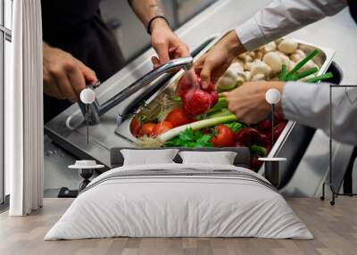 Close-up of cook washing vegetables in sink in commercial kitchen. Wall mural