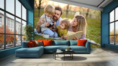 Family and small children with camera and book outdoors in spring nature, resting. Wall mural