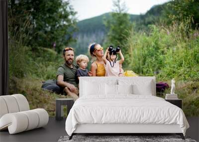 Family with small children hiking outdoors in summer nature, sitting and resting. Wall mural