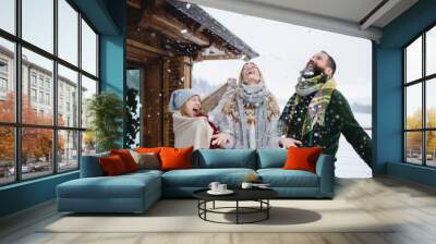 Family with small daughter having fun on terrace outdoors, holiday in winter nature. Wall mural