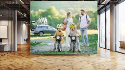 Family with two small children going on cycling trip in countryside. Wall mural