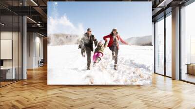 Father and mother with their daughter, playing in the snow. Wall mural