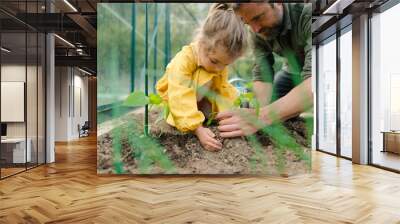 Father learning his little daughter to care about organic plants in eco greenhouse, sustainable lifestyle.Close up. Wall mural