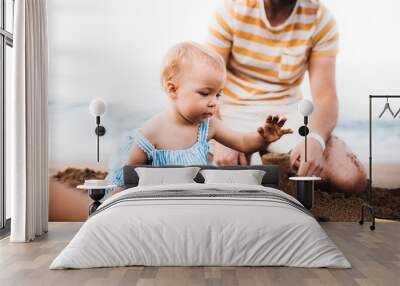 Father with a toddler girl playing on beach on summer holiday. Wall mural