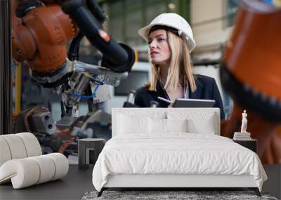 Female chief engineer in modern industrial factory using tablet and making audit. Wall mural