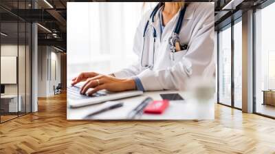 Female doctor with laptop working at the office desk. Wall mural