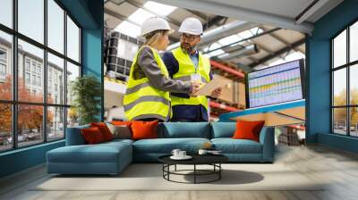 Female engineer and male project manager standing in modern industrial factory, talking about production. Team management in manufacturing facility Wall mural