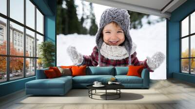 Front view portrait of cheerful small girl standing in winter nature, looking at camera. Wall mural