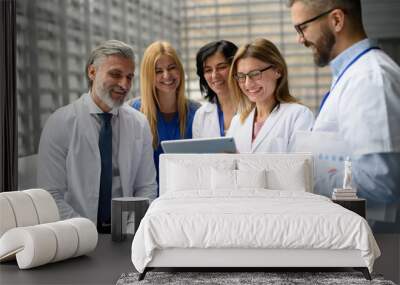 Group of doctors discussing test results, looking on tablet, medical team discussing patients diagnosis, searchign for right treatment. Wall mural