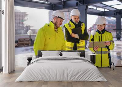 Group of engineers standing outdoors on construction site, using tablet. Wall mural