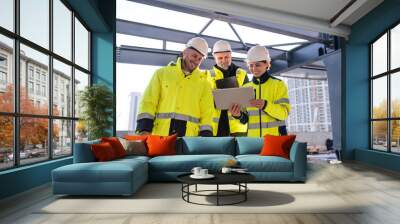 Group of engineers standing outdoors on construction site, using tablet. Wall mural