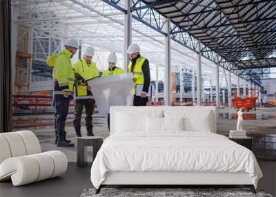 Group of engineers with blueprints standing on construction site. Wall mural