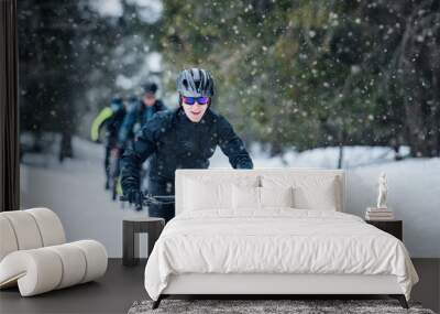 Group of mountain bikers riding on road outdoors in winter. Wall mural