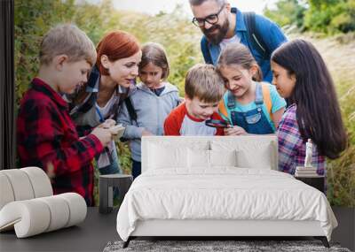 Group of school children with teacher on field trip in nature, learning science. Wall mural