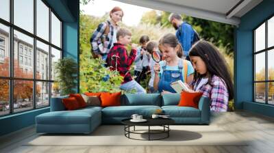 Group of school children with teacher on field trip in nature, learning science. Wall mural