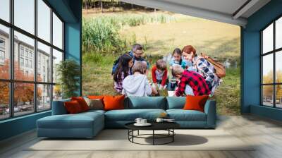 Group of school children with teacher on field trip in nature. Wall mural