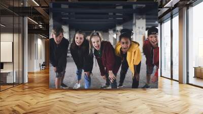 Group of teenagers gang standing indoors in abandoned building, looking at camera. Wall mural