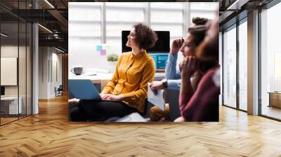 Group of young businesspeople in office, listening to a presentation. Wall mural