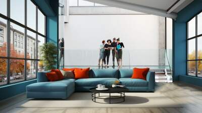 Group of young businesspeople standing near a staircase, talking. Wall mural