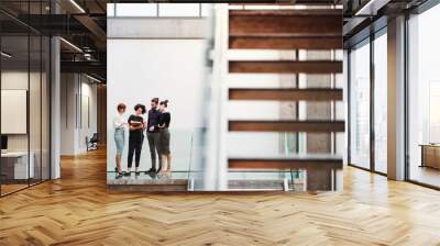 Group of young businesspeople standing near staircase, talking. Wall mural