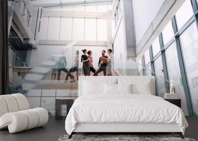 Group of young businesspeople standing on a staircase, talking. Wall mural