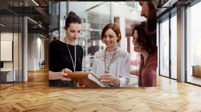 Group of young businesspeople standing together in office, talking. Wall mural