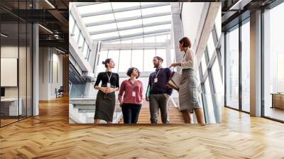 Group of young businesspeople walking down the stairs, talking. Wall mural