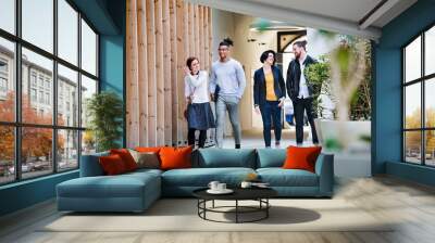 Group of young businesspeople walking outdoors in courtyard, talking. Wall mural