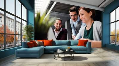 Group of young businesspeople working together in office, talking. Wall mural