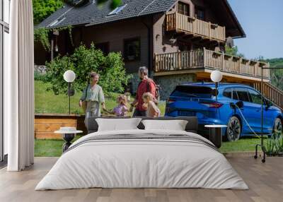 Happy family preparing for holiday, charging their electric car. Wall mural