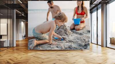 Happy family with little kids enjoying time at sea in exotic country, building sand castle. Wall mural