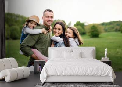 Happy family with two small daughters standing outdoors in spring nature. Wall mural