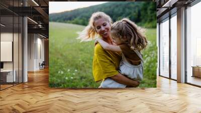 Happy mother spending time with her little daughter outside in green nature. Wall mural