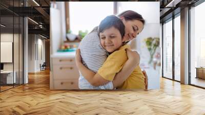 Happy oung mother hugging her little son in kitchen at home. Wall mural