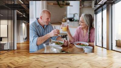 Happy senior couple eating dinner together at home. Wall mural