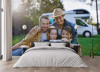 happy young family with two children ltaking selfie with caravan at background outdoors. Wall mural